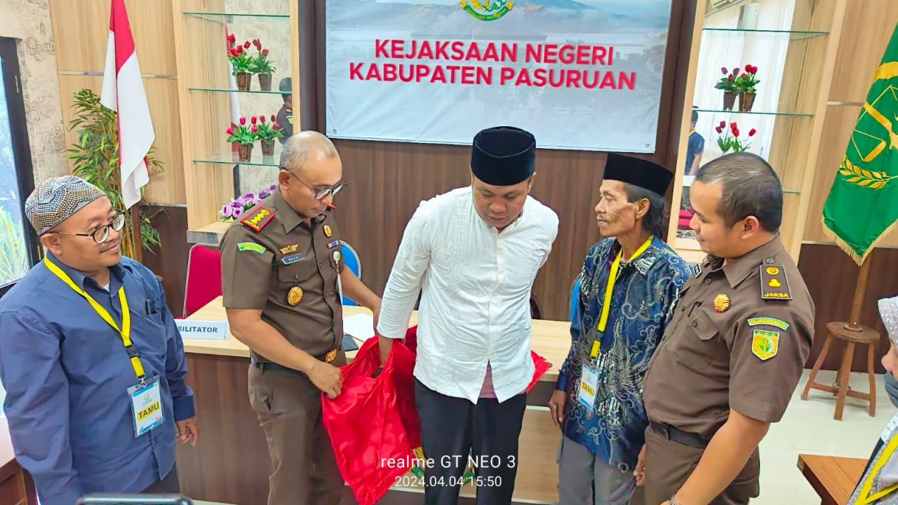 Kajari Kabupaten Pasuruan Abdi Reza Pachlewi Junus membantu melepaskan rompi warnah merah dipakai M Rizki tersangka penadah.