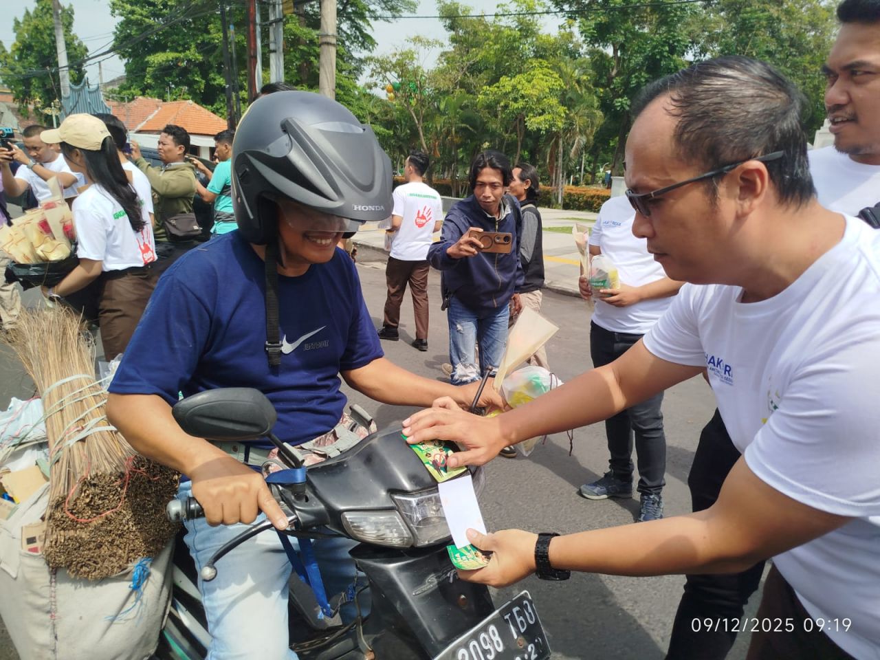 Kasi Intel Kejari Kabupaten Pasuruan, Ferry Hary Ardianto saat membagikan stiker kepada pengguna jalan raya dalam memperingati Hakordia 2025