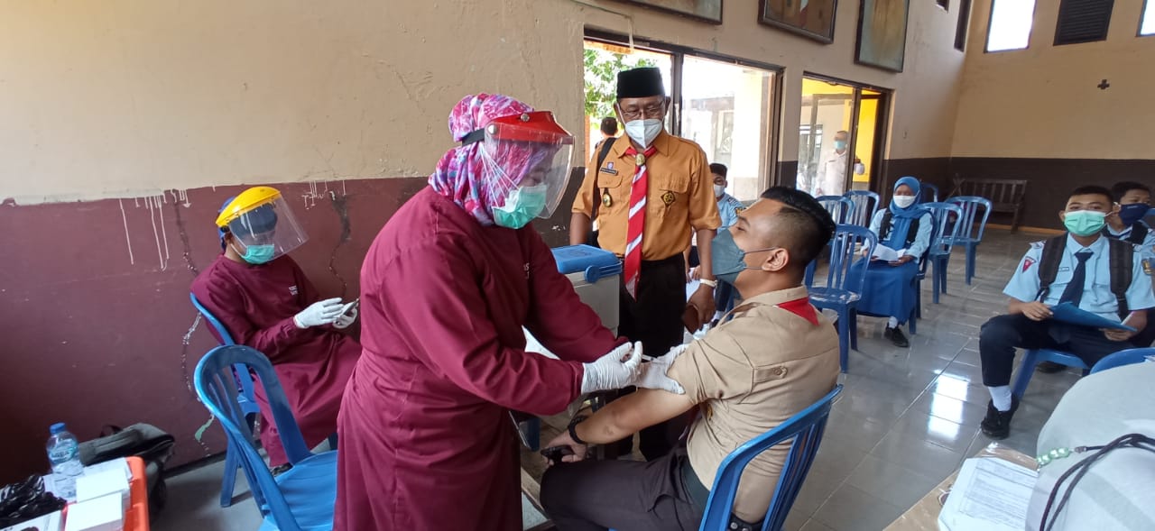 Anggota pramuka lagi mendapat suntik vaksin dosis pertama disaksikan sekretaris Kwarcab Ponorogo Kak Tri.