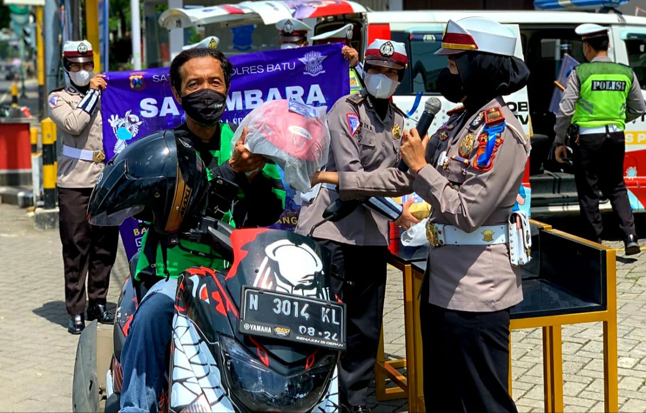 Kasat Lantas Polres Batu saat memberi hadiah helm kepada pengendara bermotor