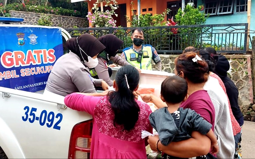 Anggota Satlantas Polres Batu saat bagi - bagi sayur gratis