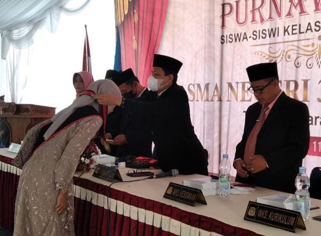 DR.Sasmito Pribadi mengalungkan Gordon kepada siswa klas XII